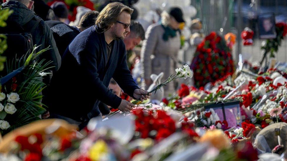 A man lays flowers outside the concert hall