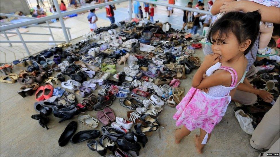 A Colombian girl who was deported looks on next to donated shoes in a temporary shelter