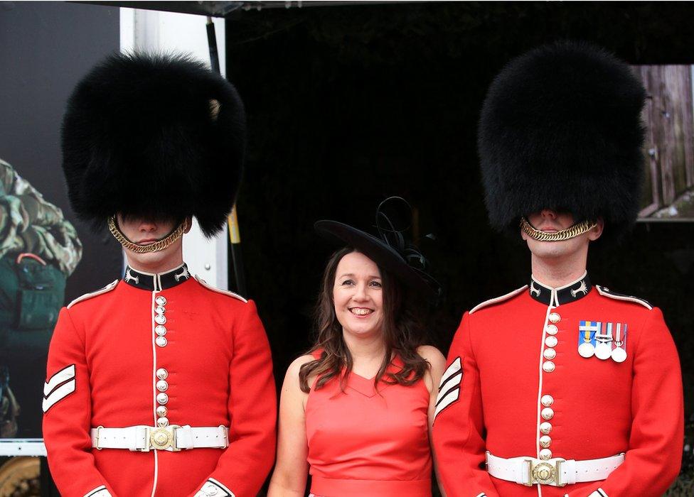 A lady stands between two of the Queen's Guard