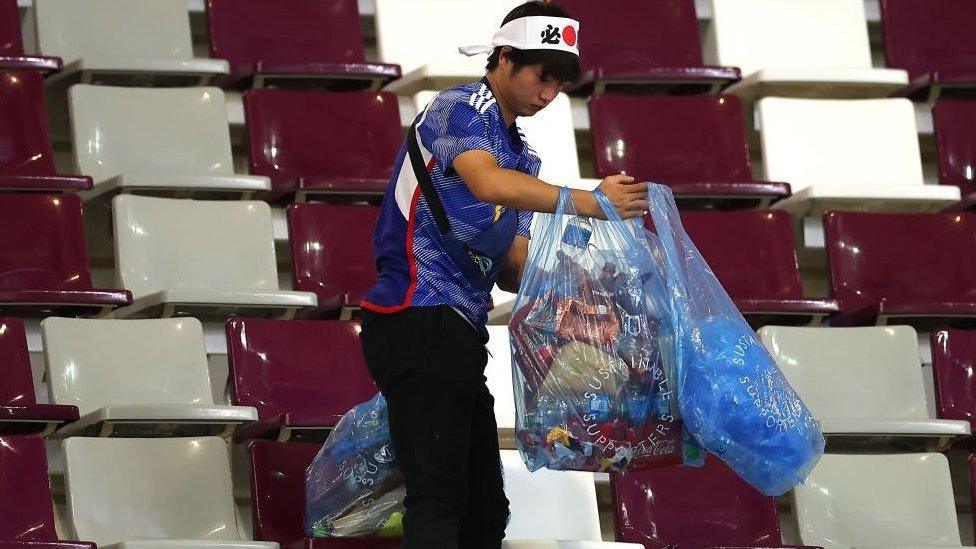 A Japan fan holding bags full of rubbish