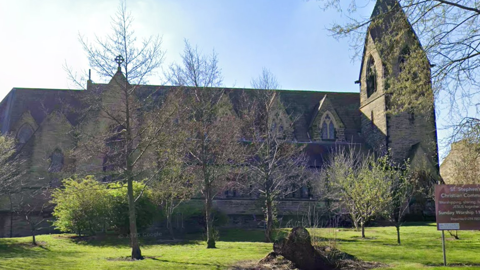 A large Victorian church with trees and grassed area in front of it