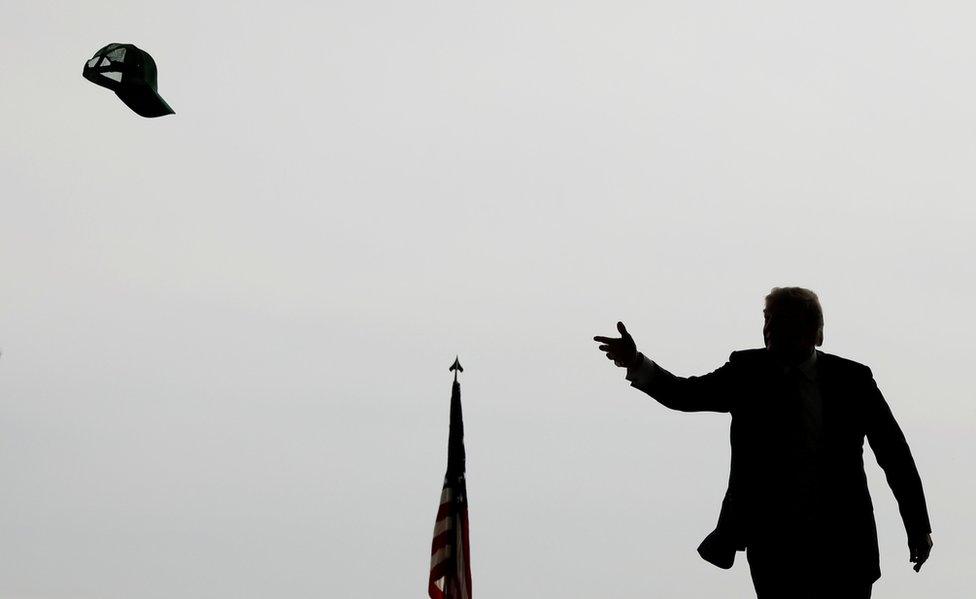 President Donald Trump tosses a hat into the crowd