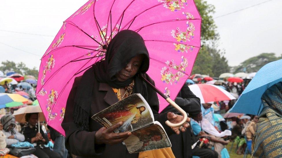 Woman prays under umbrella