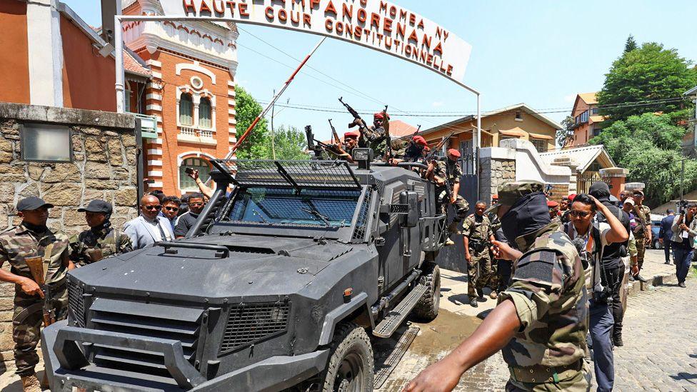 A black armoured vehicle surrounded by soldiers leaves the High Constitutional Court in Antananarivo