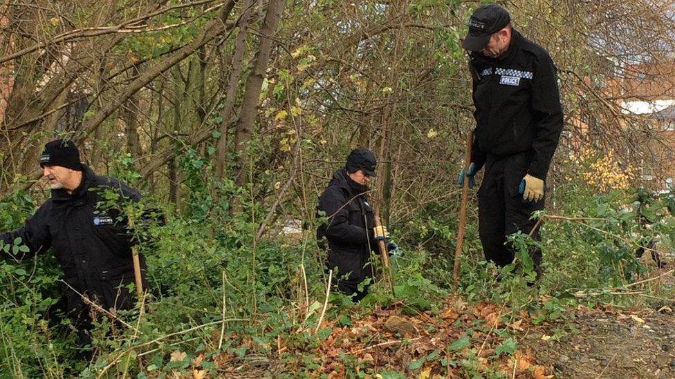 Police officers searching river bank