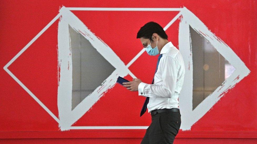 Man walks past HSBC sign