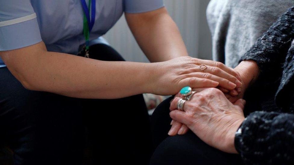 A care worker holding the hands of an older person.