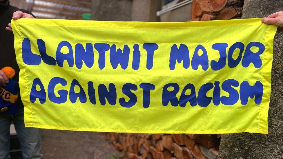 Annie and her husband holding a homemade banner saying "Llantwit Major against racism"