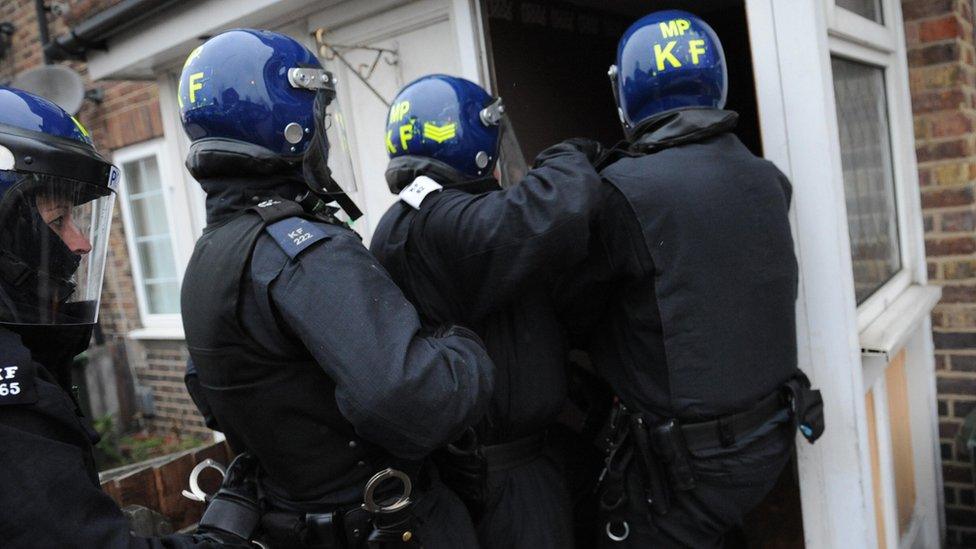 Met Police officers prepare to raid an address in east London as part of an operation to arrest leaders of violent gangs