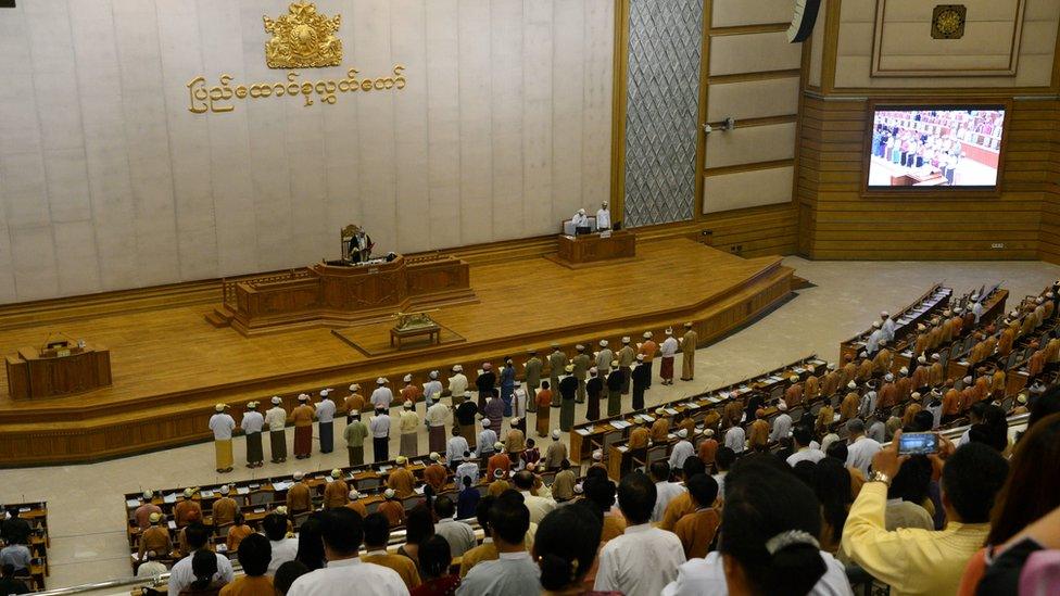 New Myanmar Ministers including the country's democracy icon Aung San Suu Kyi (front row 9th R, in blue) are sworn into office by Upper House Speaker Mahn Win Khine (on podium) during a ceremony at the parliament in Naypyidaw on March 30, 2016.