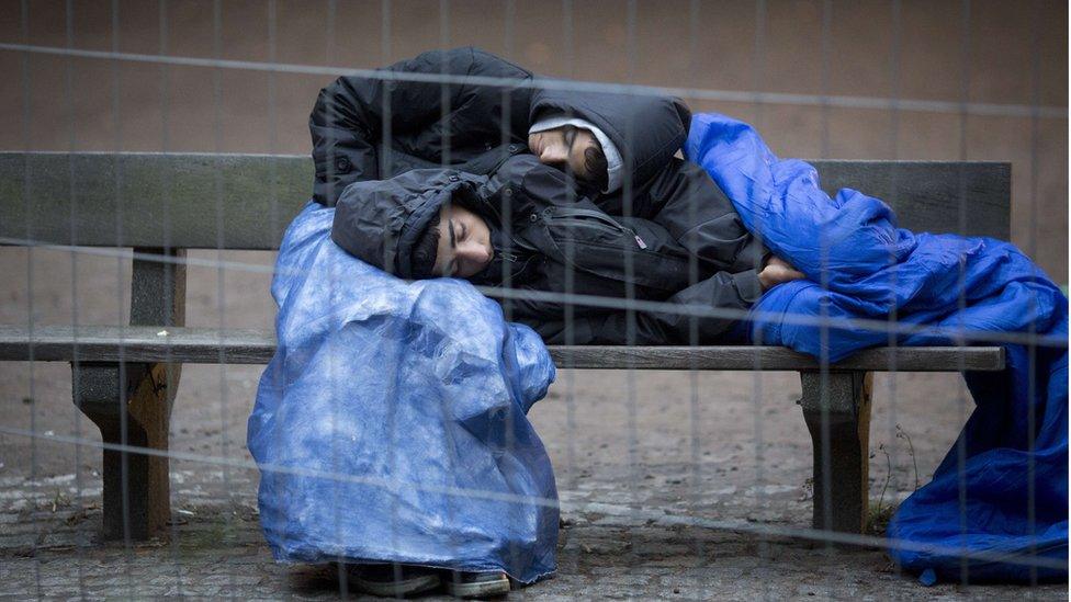 Two refugees sleep on a bench on the grounds of the State Office of Health and Social Affairs (LAGeSo) in Berlin on 9 October 2015, where they wait for their registration.