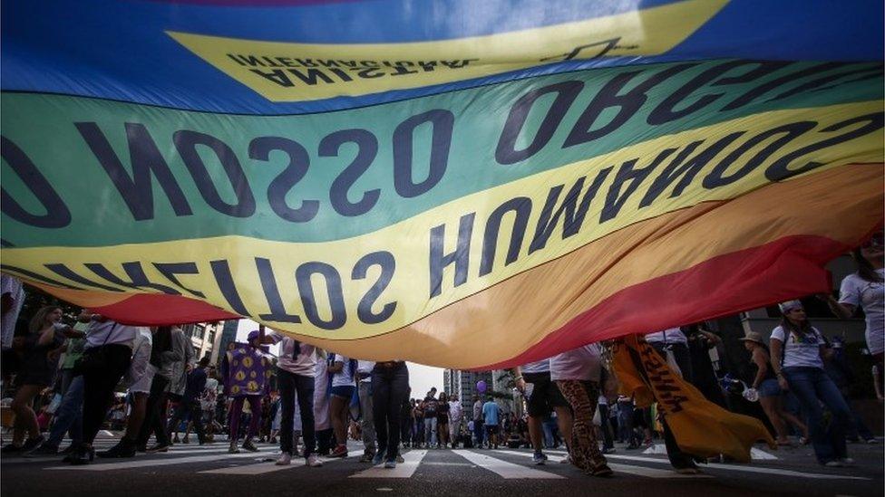 People attending Sao Paulo's Gay Pride parade carry a rainbow flag