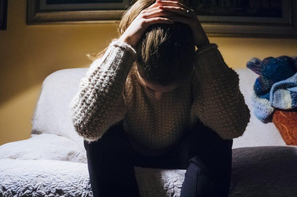 Woman sat on bed looking sad