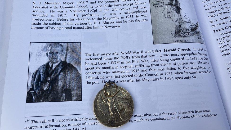 page of book with information about Harold Crouch, with medal resting on top.