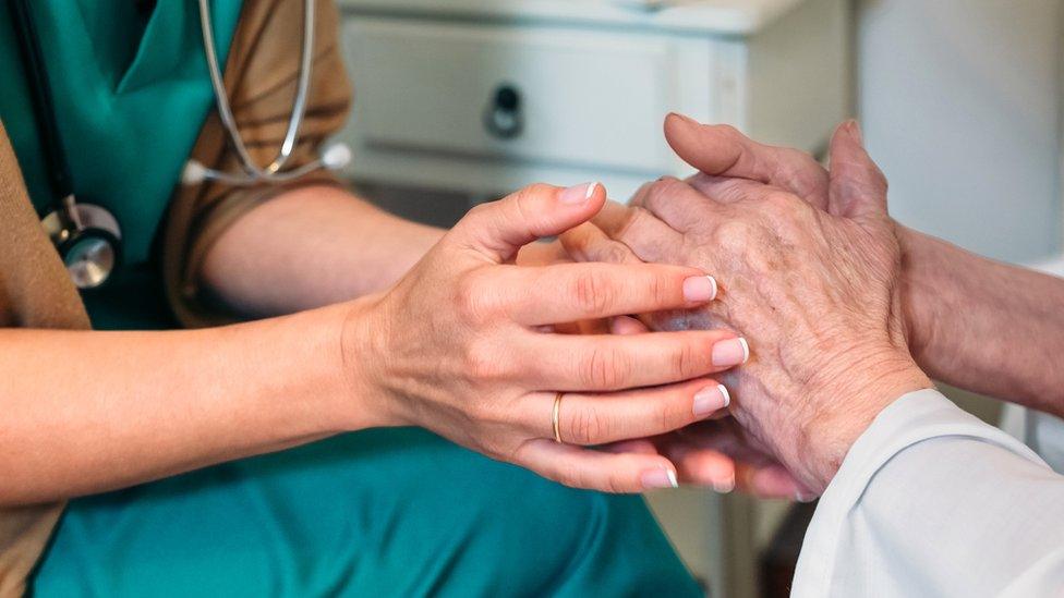 Medical member of staff holding the hands of a patient