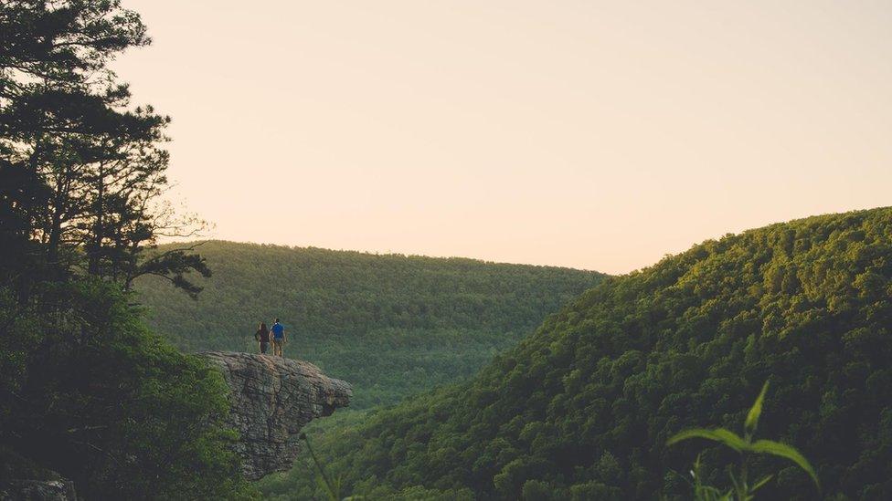 The couple standing and looking at the view from the crag