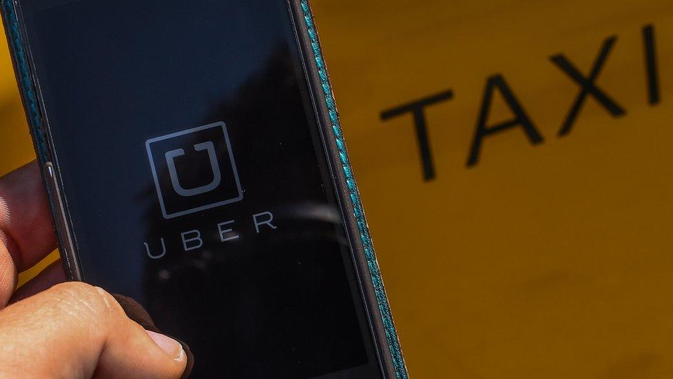 In this photo illustration, the new smart phone app 'Uber' logo is displayed on a mobile phone next to a taxi on July 1, 2014