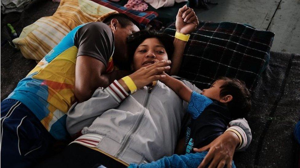 A migrant family rests on blankets in a Mexico City stadium