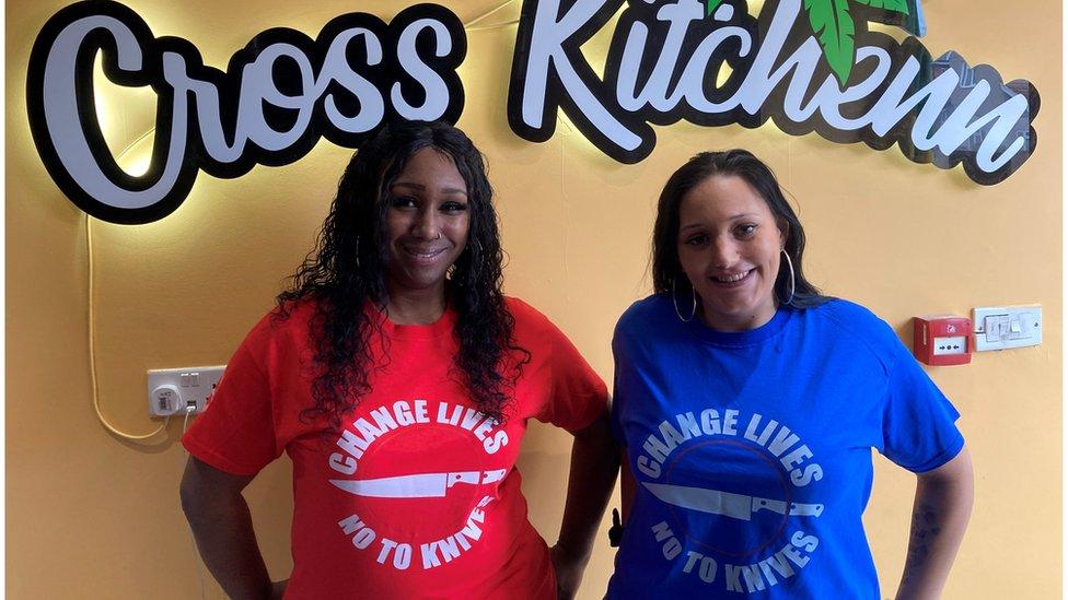 Ms King and Ms Turner, Cross Ktichenn ambassadors and founders of the charity Change Lives No to Knives standing under a sign that reads Cross Kitchenn