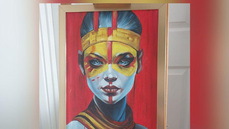 Painting of a woman. She has yellow paint around her eyes and a blue face.
The canvas behind her has been painted red