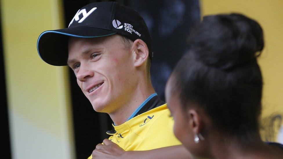 Britain"s Chris Froome gets his yellow jersey adjusted. It shows he's the leader of the Tour De France.