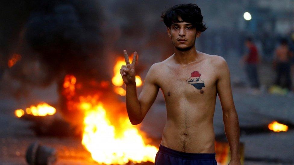 A demonstrator flashes the victory sign during a protest over poor public services in Baghdad on 27 July