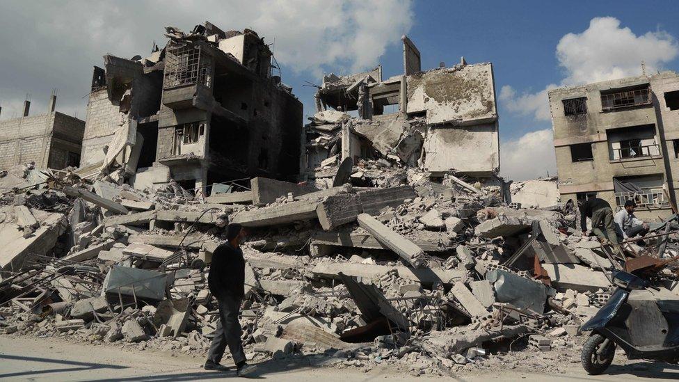 A man walks past destroyed buildings in Douma, in the besieged rebel-held Eastern Ghouta area of Syria (28 February 2018)