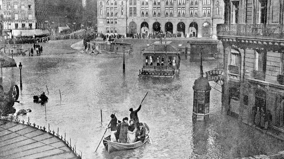 people in boats on the water in a big square, going between restaurants and cafe