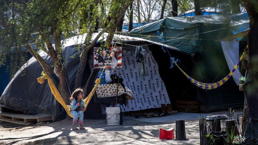 A Salvadorian girl sits near a Biden-Harris campaign poster inside a camp for asylum seekers on February 07, 2021 in Matamoros, Mexico