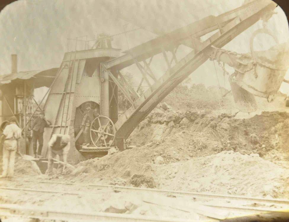 Steam engine workers Mugdock showing workers using a large steam-driven trencher for digging trenches