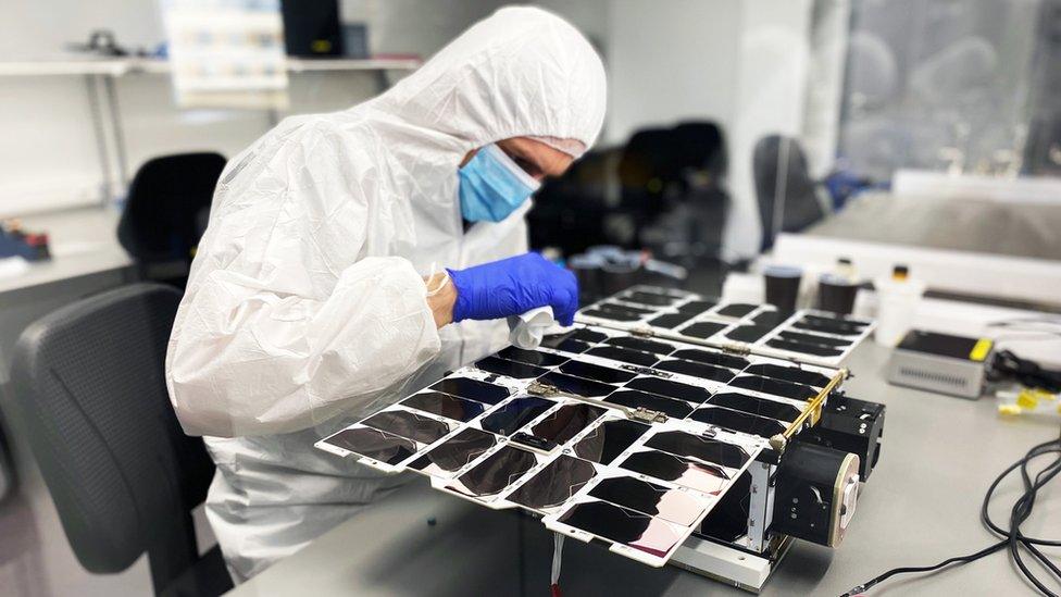 A NanoAvionics engineer assembling a nanosatellite