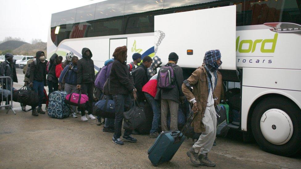 Refugees wait to board a bus