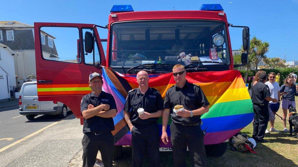 fire officers with LGBTQ+ flag on its fire truck vehicle