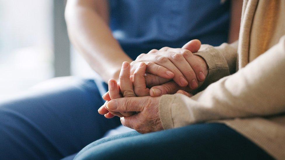 Cropped shot of a senior woman holding hands with a nurse