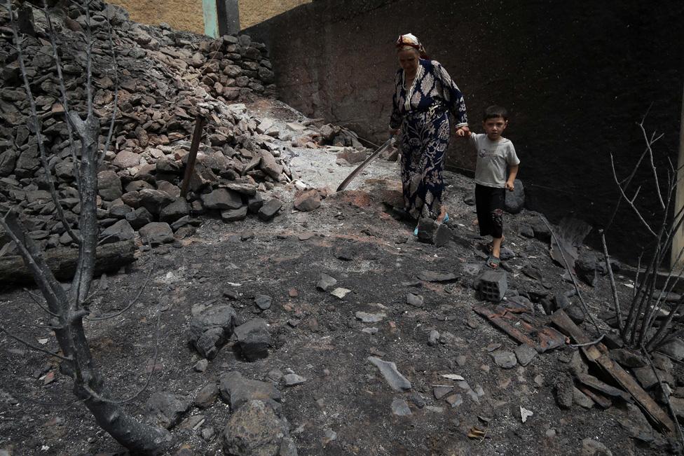 A woman and child walk through burned housed in the village of de Oeud Das in Bejaia in Algeria