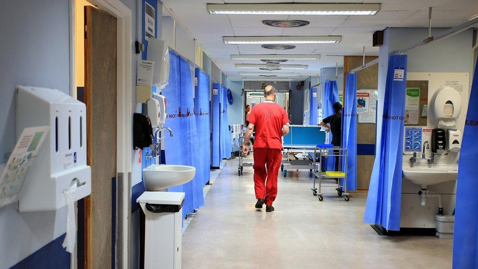 A doctor walks along a hospital ward