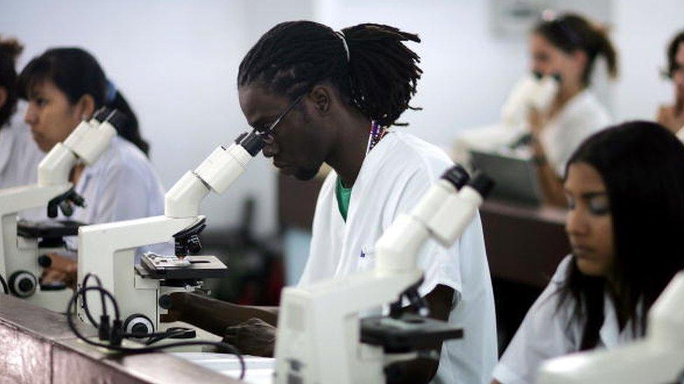 Jamar Williams (C) from Brooklyn, New York looks through a microscope during a class while attending the Latin American School of Medical Sciences December 4, 2006 in Havana, Cuba.