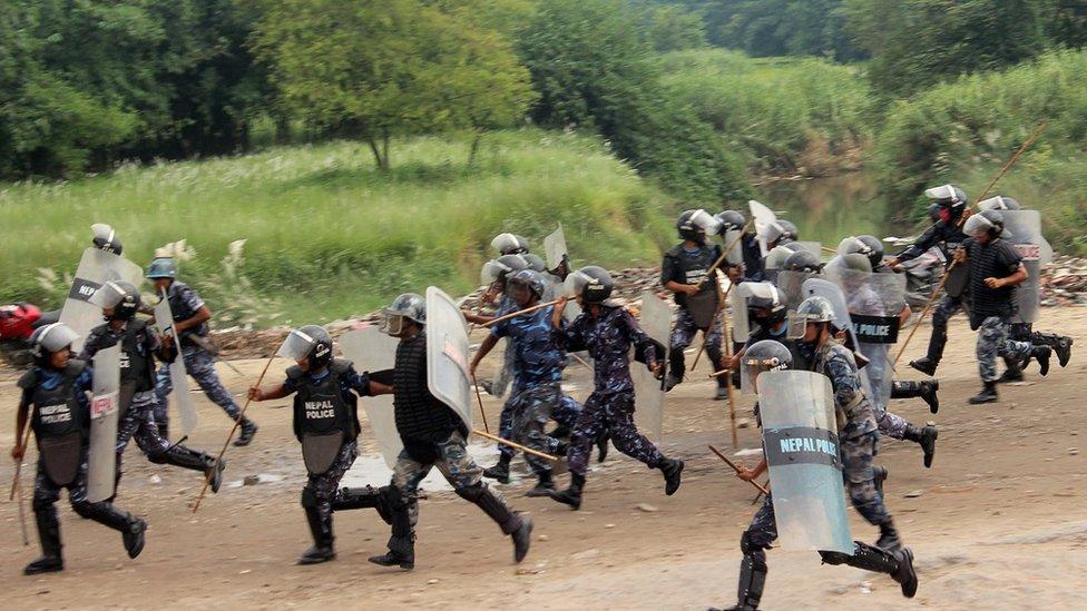 Nepalese policemen run for cover as they are chased by protestors belonging to ethnic and religious groups in Birgunj