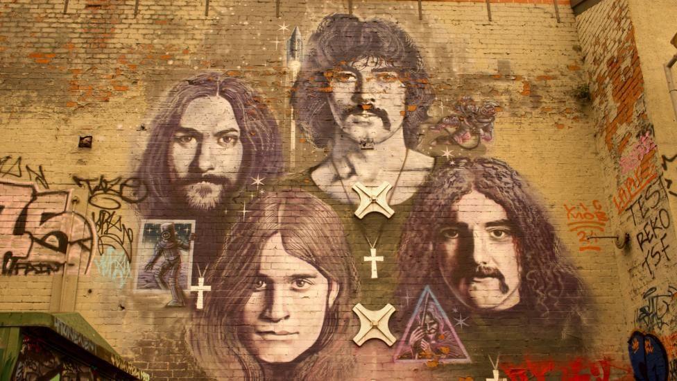 A mural on a brick wall of Black Sabbath band members