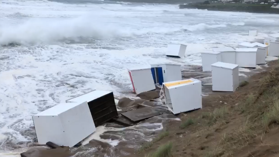 Beach huts entering water on Woolacombe beach