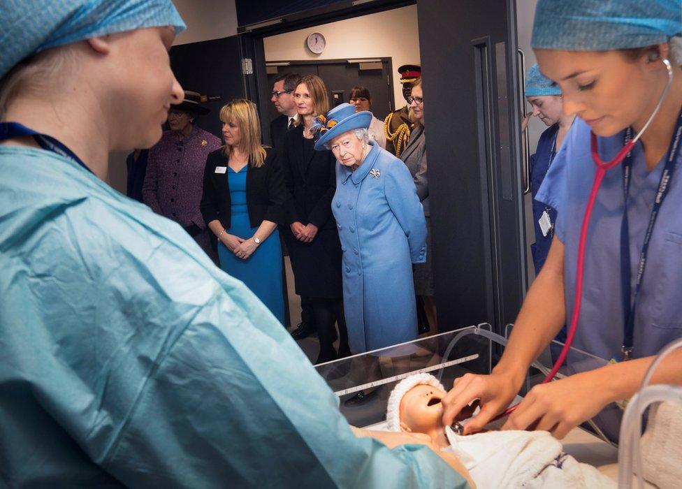 The Queen watching a demonstration in shown in an operating theatre