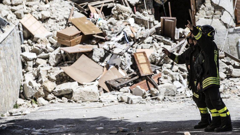 Fire crews stand near rubble in Arquata, Italy