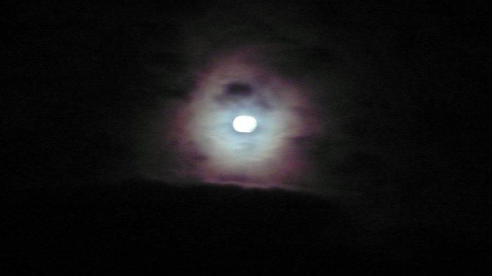 supermoon piercing the early morning clouds in Ullapool