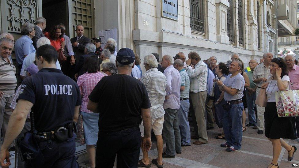 A policeman maintains order as Greek pensioners, who do not own an ATM card, line up to get part of their pensions in front of a branch of National Bank of Greece in Athens