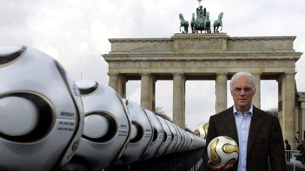 Franz Beckenbauer, president of Germany's World Cup organising committee, holds a golden soccer ball during a presentation next to the Brandenburg Gate in Berlin, 18 April 2006