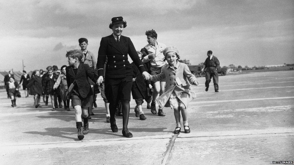 London Airport traffic clerk Doreen Haines walking French children along the runway to their plane home, 12 September 1946