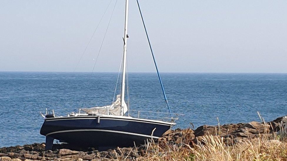 Yacht on a rocky gully off Raz at Longis Bay, Alderney