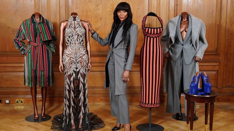 Naomi Campbell alongside a range of designs including a striped coat, crystal embellished gown, striped dress, Hugo Boss suit and blue platform shoes