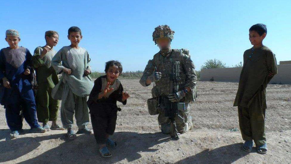 Ben Baker in combat gear with Afghan children