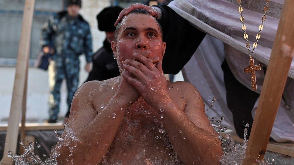 A priest conducts an Epiphany ceremony with a worshipper